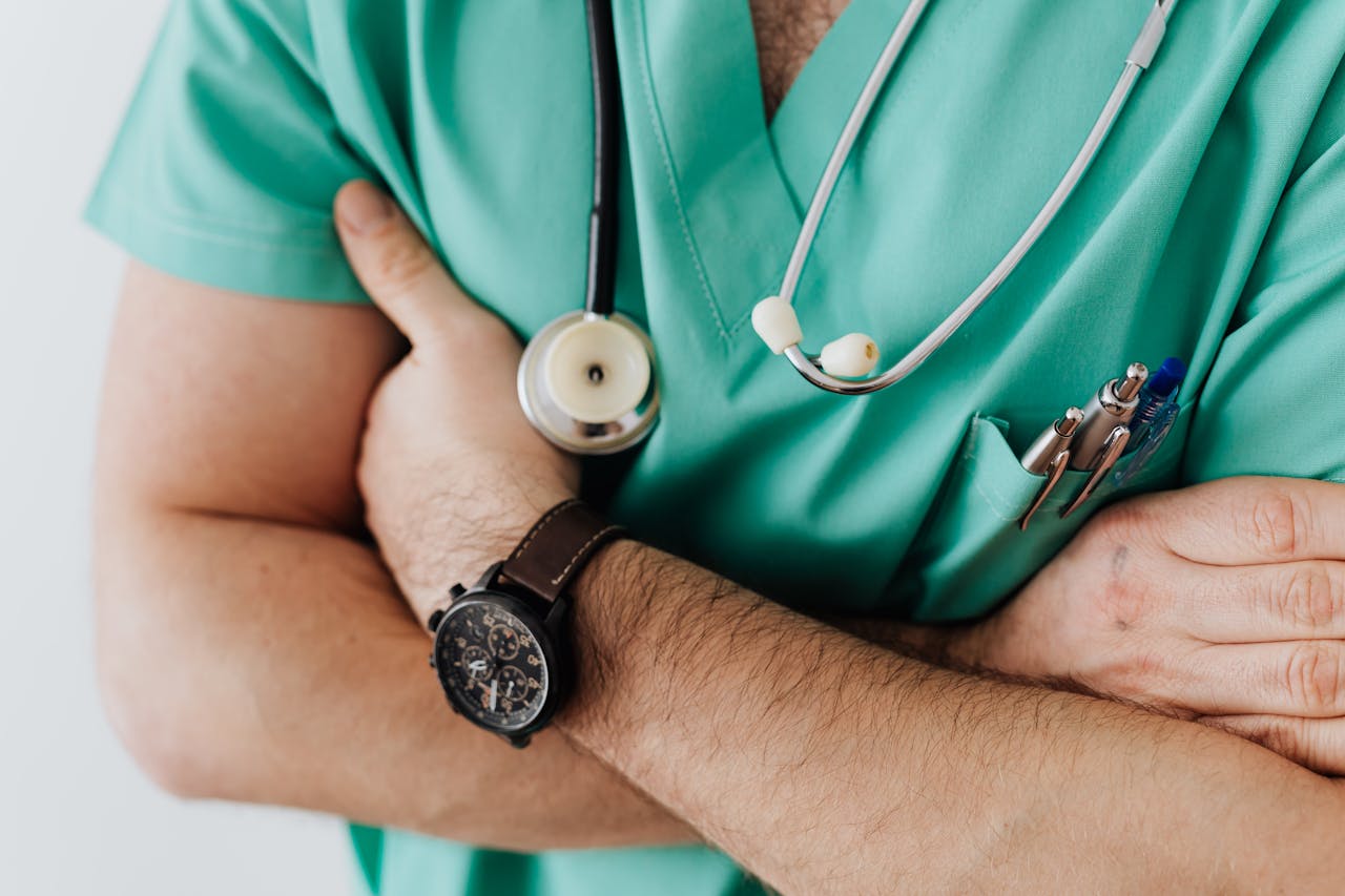 Home Doctor in scrubs with folded arms and stethoscope, symbolizing confidence in healthcare.