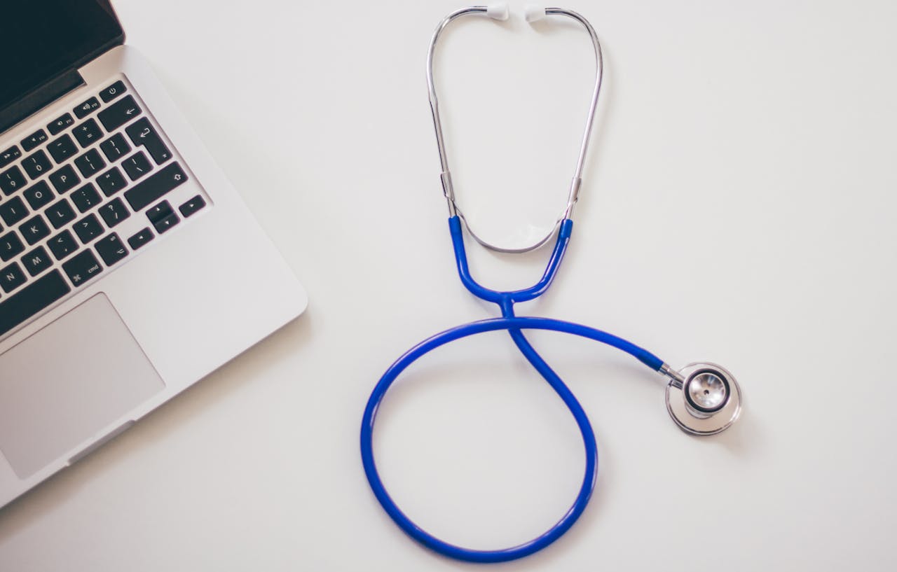 Home Medical stethoscope and laptop on a white desk, symbolizing digital health solutions.